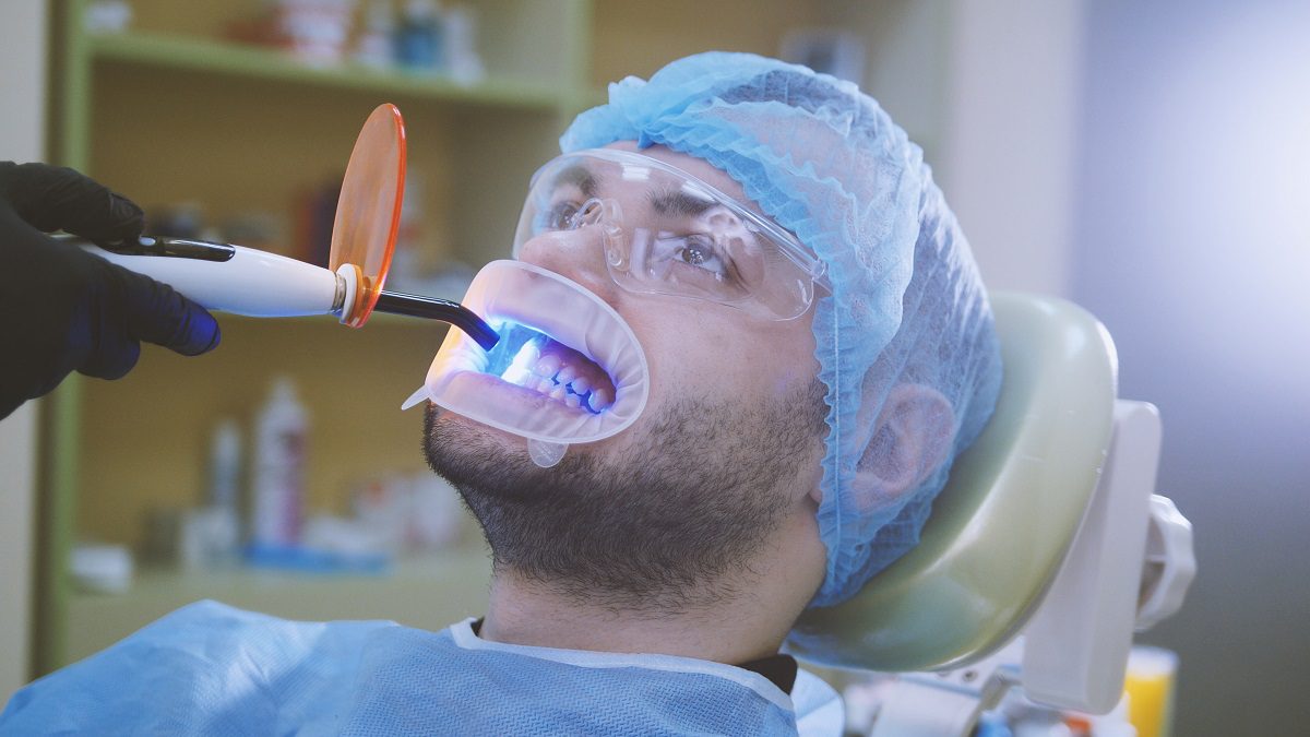 doctor-patient-with-retractor-dental-office-cleaning-with-ultraviolet-light-orange-pr.jpg