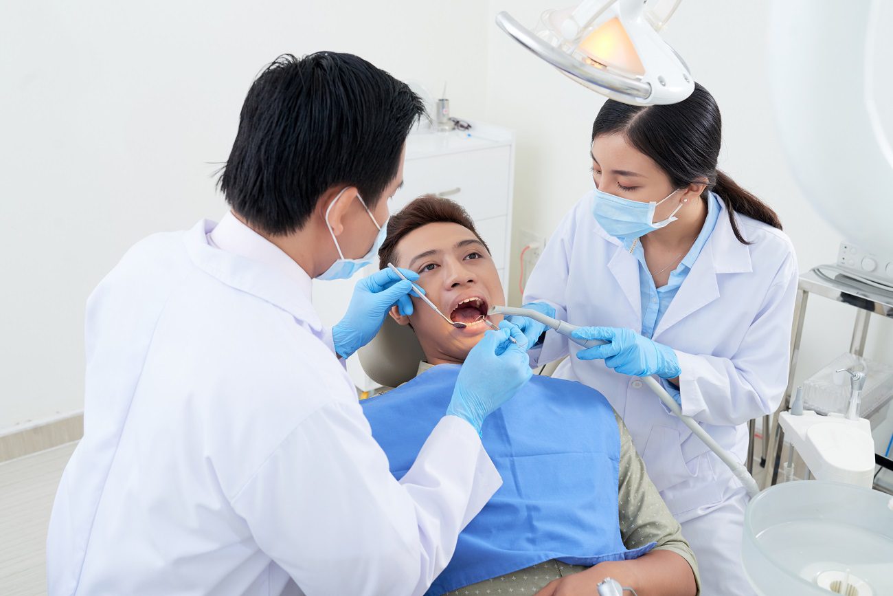 male-dentist-nurse-examining-asian-patient-s-teeth-clinic.jpg